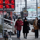 People walk past a money exchange office with a sign showing currency exchange rates in Moscow, Tuesday, Jan. 20, 2015. The Russian currency has lost half of its value in one year under a combined blow of slumping oil prices and Western sanctions over Ukraine. (AP Photo/Pavel Golovkin)